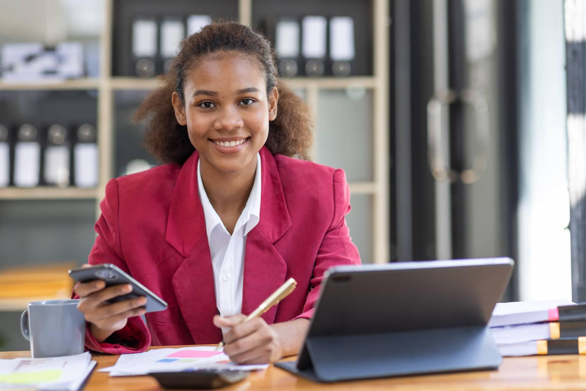 woman behind desk with smartphone