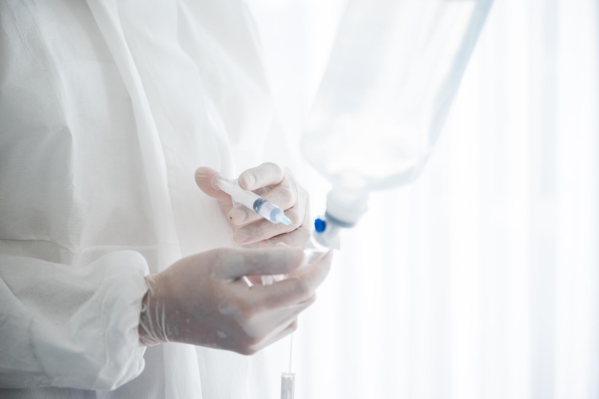 A man in a lab coat sticking a needle through a bag