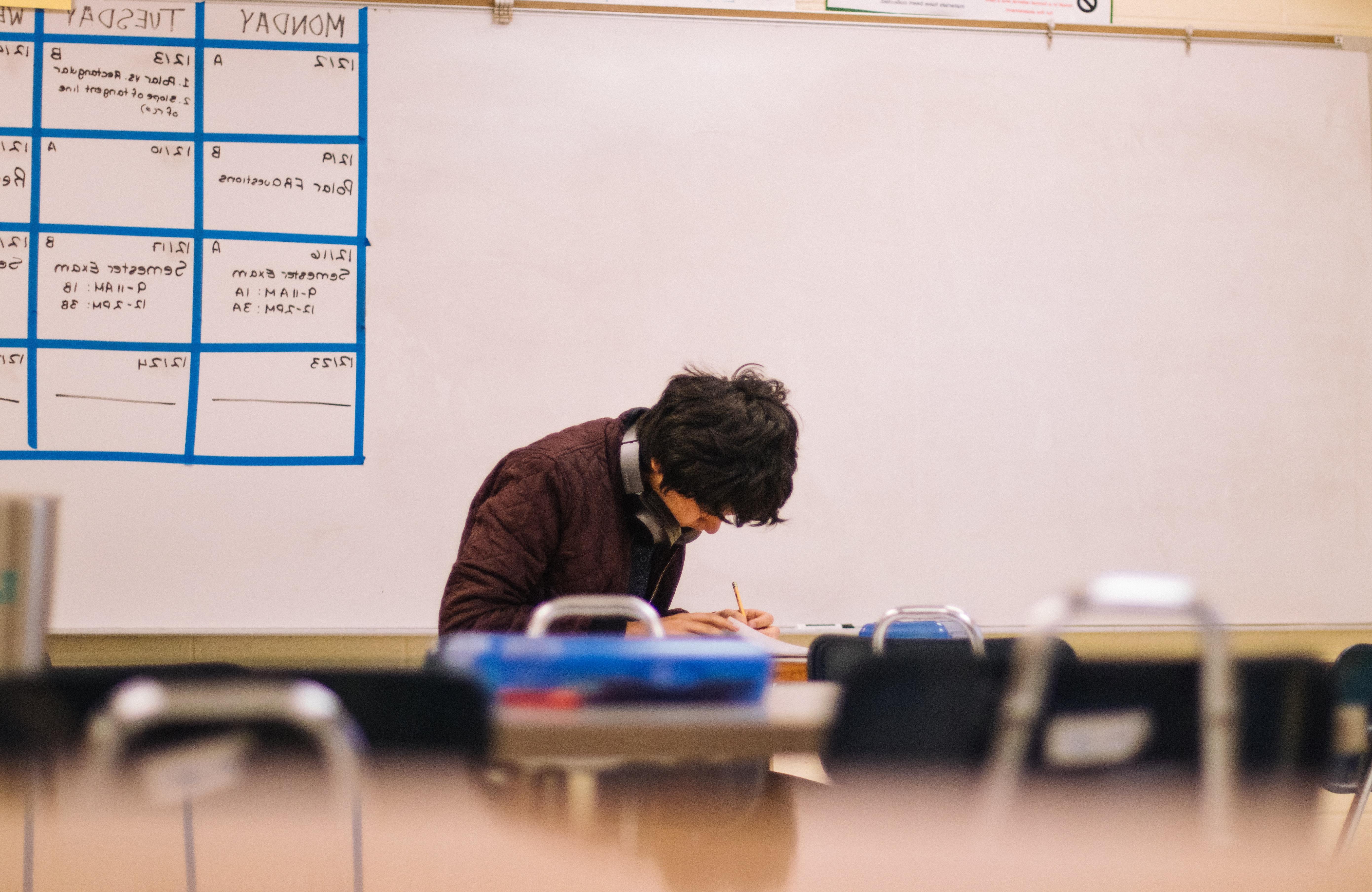 A male student working at his desk by himself